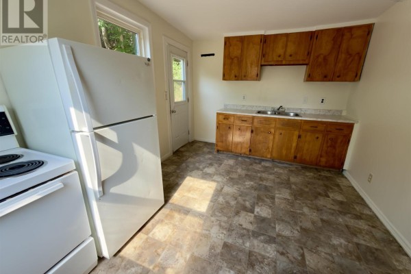 Kitchenette with wood cabinets, white appliances, and a door leading outside. - 13 Chester Avenue, Kentville