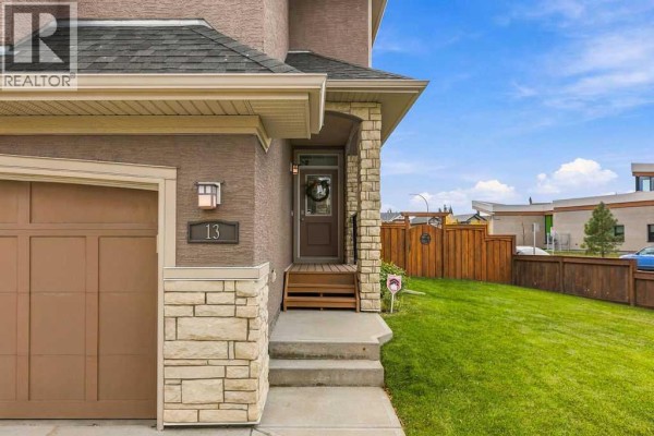 Close-up of the front entrance of the house, showing the address number 13, front door, and grass lawn. - 13 Cranford Gardens Se, Calgary