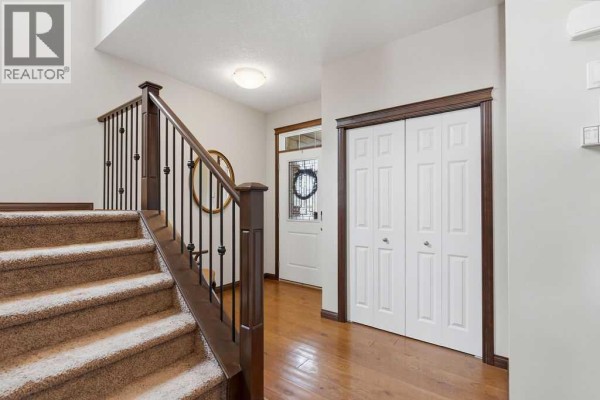 View of the foyer and staircase with dark wood trim and carpeted steps, leading to the upper floor. - 13 Cranford Gardens Se, Calgary