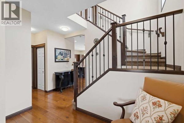 Interior view of the foyer and staircase, showing a console table, doorway, and access to the kitchen. - 13 Cranford Gardens Se, Calgary