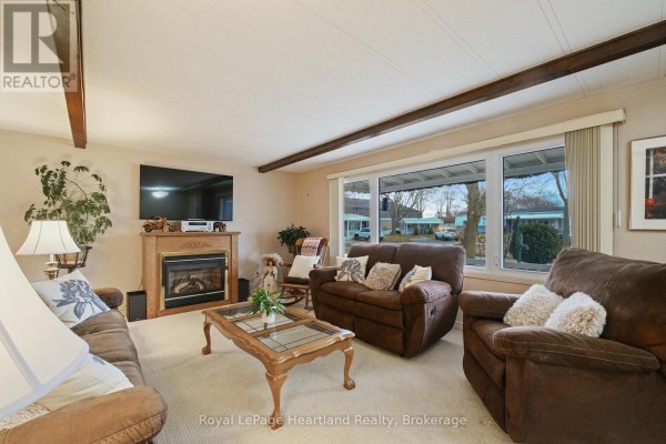 Bedroom with a ceiling fan, large window, and a dresser, featuring neutral decor - 13 Cypress Point Crescent, South Huron