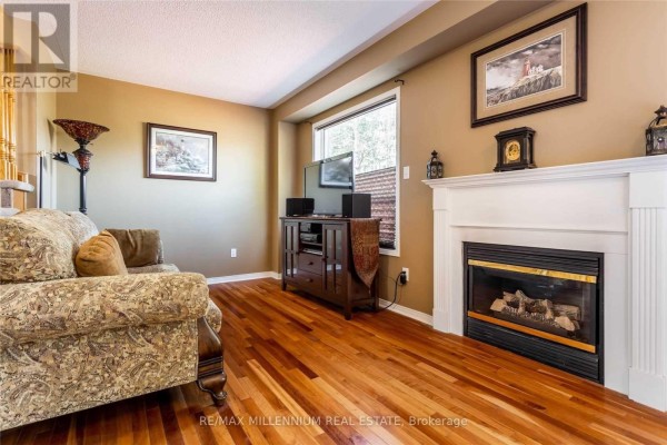 Living room with a fireplace, sofa, television, and hardwood floors. - 13 Dawson Crescent, Milton