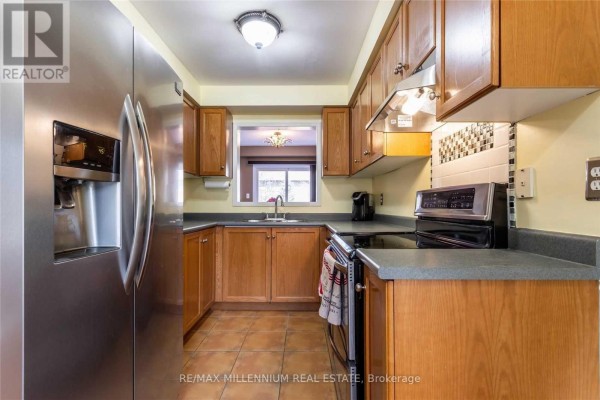 Kitchen with stainless steel refrigerator, wooden cabinets, and tiled floor. - 13 Dawson Crescent, Milton