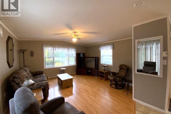 Living room with wood laminate floors, sofa, chairs, and television stand. - 13 Du Bouleau Street, Saint Jacques
