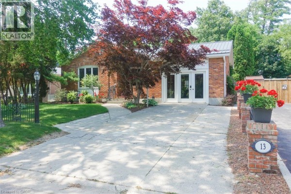 Exterior view of a brick house with a large driveway and manicured lawn. - 13 Kelly Avenue, Simcoe
