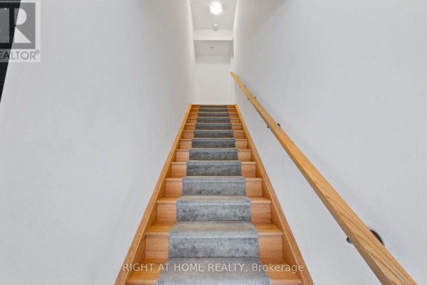 Wooden staircase with grey carpet runner ascends between white walls with a wooden handrail. - 13 Magnolia Lane, Barrie