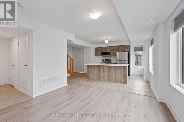 View from kitchen into living space, showing island, cabinetry, and stairs to another level. - 13 Magnolia Lane, Barrie