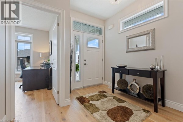 Interior foyer with light wood floors, a white front door, and a dark console table with decor. - 13 Masters Lane, Paris