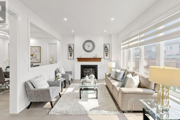Living room with a fireplace, neutral sofa, grey armchairs, and a large window. - 13 Micklefield Avenue, Whitby