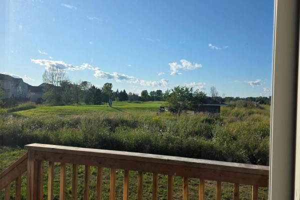 View from a wooden deck looking out over a green golf course with trees and houses in the distance. - 13 Oakmont Drive, Loyalist