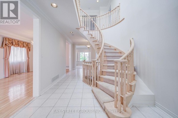 A spacious living room with a fireplace, large window with shutters, and light wood floors. - 13 Pembrooke Road, Markham