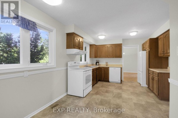Kitchen with wooden cabinets, white appliances, and large window - 13 Shanel Place Ottawa