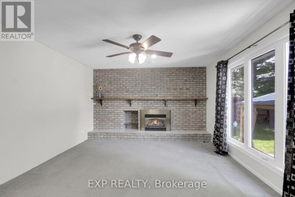 Living room with brick fireplace and large windows - 13 Shanel Place Ottawa