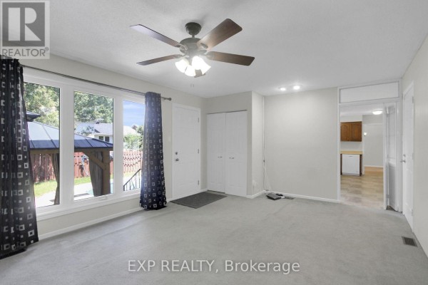 Living room with ceiling fan, large windows, and backyard view - 13 Shanel Place Ottawa
