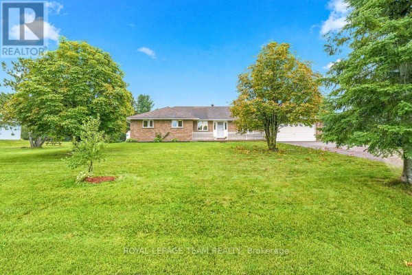 Front exterior of a brick bungalow with a green lawn and mature trees in the yard. - 13 Springfield Drive, Whitewater Region