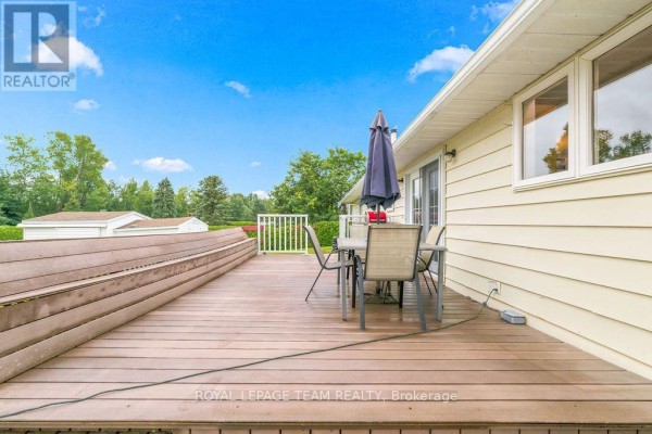 Deck with patio set and umbrella, detached garage, and white railing - 13 Springfield Drive Whitewater Region