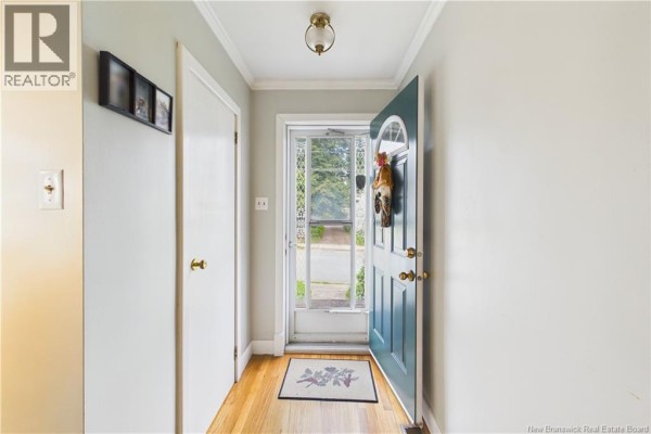 Interior hallway with an open front door, showing a screen door and a wooden floor. - 13 Squire Street, Sackville