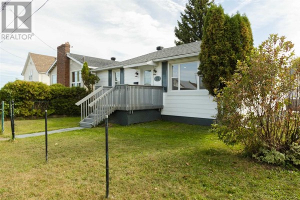 Exterior of a white bungalow showing the entrance stairs and surrounding green lawn. - 13 Stevens St, Sault Ste  Marie