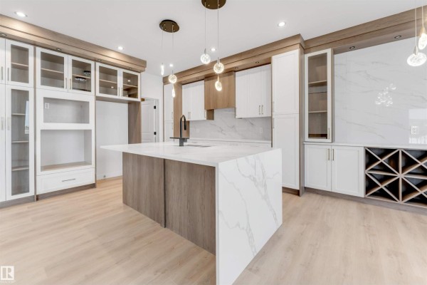 Open-concept living area with a modern kitchen island, pendant lighting, and large windows. - 13 Trill Pt, Spruce Grove