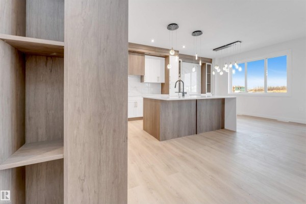 Spacious living area with a view of the kitchen, large windows, and a modern fireplace. - 13 Trill Pt, Spruce Grove