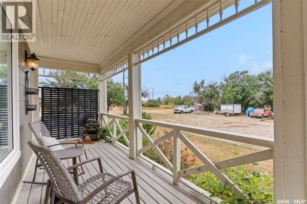 View from the porch of rural property with chairs, tables, and distant vehicles and sheds. - 13.04 Acreage By Lake Diefenbaker, Canaan Rm No  225