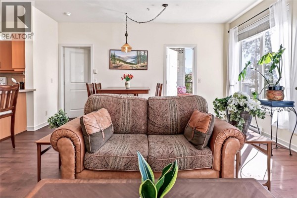 View of a living room sofa, dining table, and doorway leading to a balcony. - 130 Barber Road Unit# 103, Kelowna