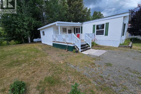 Side exterior view of the mobile home showing the covered porch with white railing. - 130 Ferry Road Unit# 7, Clearwater