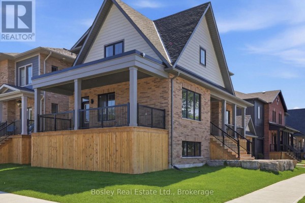Exterior of a multi-story brick home with a covered porch and wooden deck. - 130 Fifth Street, Collingwood