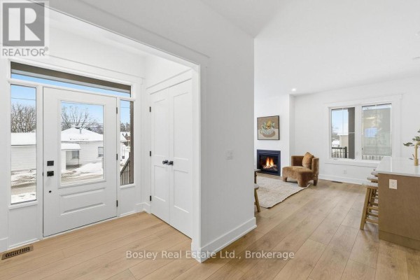 Interior foyer with white doors, hardwood floors, and view into living area with fireplace. - 130 Fifth Street, Collingwood