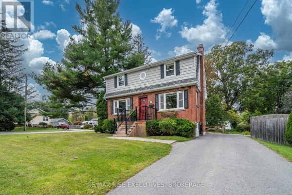 Side view of the brick house showing the driveway and surrounding trees. - 130 Florence Street, Kingston