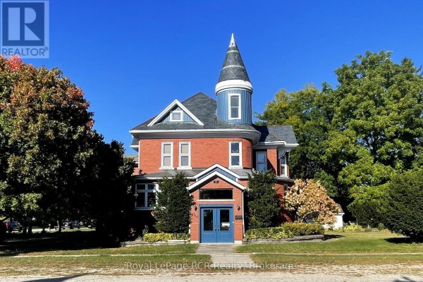 Full front exterior of a historic red brick home with blue double doors and a conical turret. - 130 John Street, North Perth