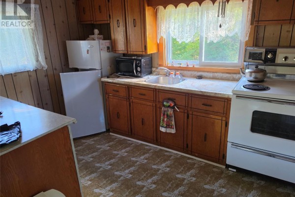 Kitchen with wood cabinets, white appliances, and patterned flooring. - 130 Mill Road, Marysvale