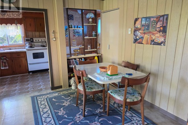 Dining area with a table, chairs, and wood-paneled walls. - 130 Mill Road, Marysvale