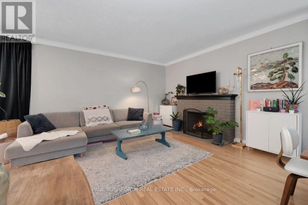 Living room with a grey sectional sofa, coffee table, and fireplace. - 1300 Field Street, Ottawa