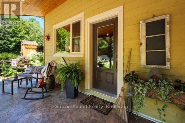 Covered front porch with seating, a rocking chair, and potted plants. - 130044 Sideroad 20 Side Road, Georgian Bluffs