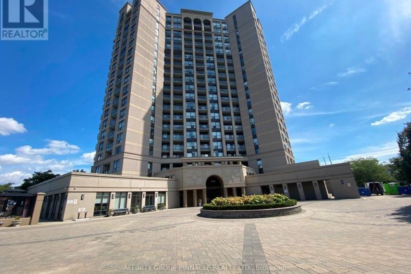 Exterior view of a tall beige condominium building with many balconies and a circular driveway. - 1301 - 220 Forum Drive, Mississauga