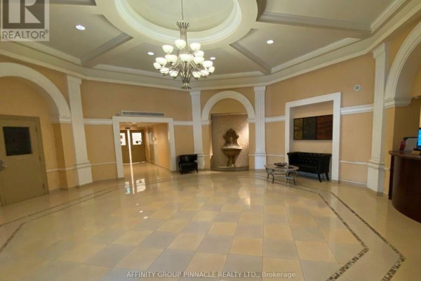 Luxury lobby with cream tiled floors, chandelier, ornate fountain, seating area, and arched doorways. - 1301 - 220 Forum Drive, Mississauga