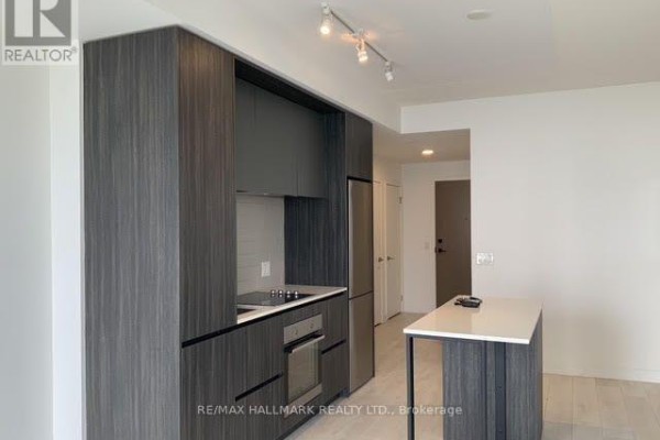 Modern kitchen with dark wood cabinets, stainless steel appliances, and a white island. - 1301 - 225 Sumach Street E, Toronto