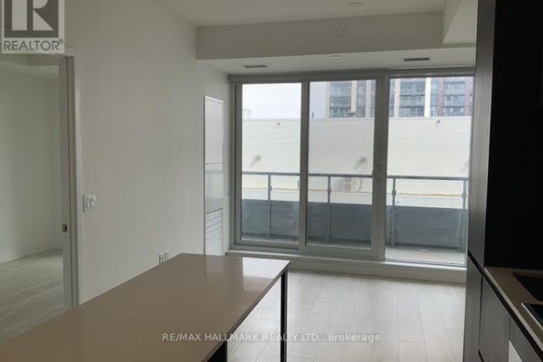 Living area with a large window overlooking the city, leading to a balcony. - 1301 - 225 Sumach Street E, Toronto