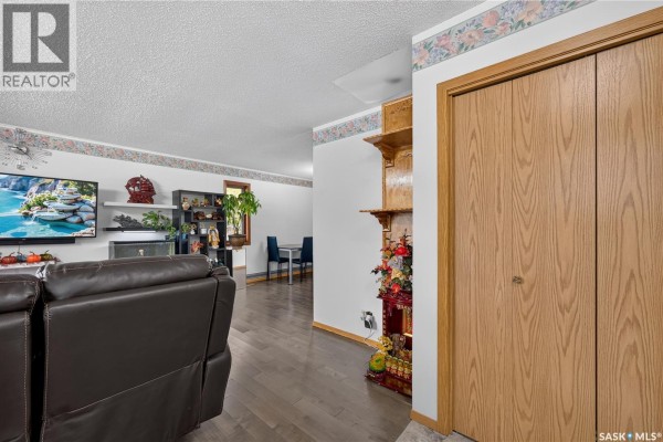 Living room with dark brown couch, fireplace, and an opening to a dining area. - 1301 King Street, Regina
