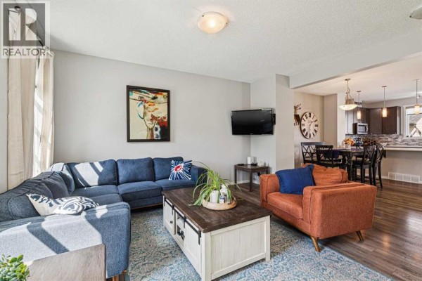 Living room with a blue sectional and view into the dining area and kitchen. - 1301 Walden Drive Se, Calgary