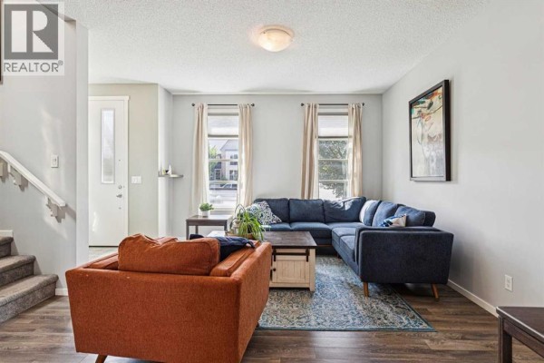 Living room with neutral walls, a sectional sofa, and a view of the entrance. - 1301 Walden Drive Se, Calgary