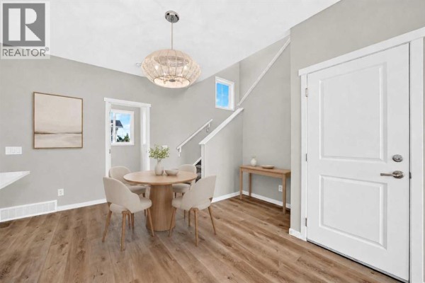 Dining area with round wooden table, chairs, and a hanging light fixture. - 1302 Mahogany Boulevard Se, Calgary