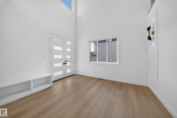 Open concept living area with a high ceiling, loft railing, and modern wall sconces. - 13024 186 Avene Nw, Edmonton