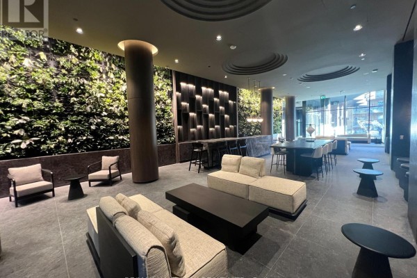 Interior view of a lobby with seating, a bar, and a dramatic vertical plant installation. - 1303 - 120 Broadway Avenue, Toronto