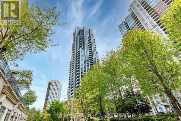 View looking up at a tall apartment building with surrounding trees. - 1303 - 15 Viking Lane, Toronto