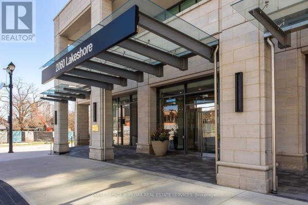 Entrance to the 2060 Lakeshore building with a stone facade, modern canopy, and glass doors. - 1303 - 2060 Lakeshore Road, Burlington