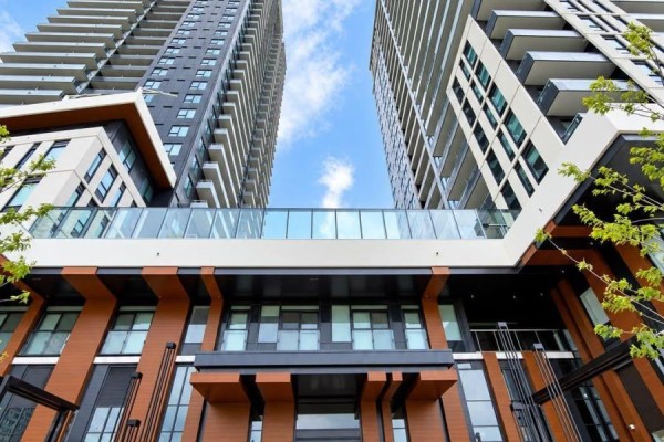 View looking up at modern high-rise apartment buildings connected by a glass skybridge. - 1303 - 21 Meadowdale Road, Vaughan