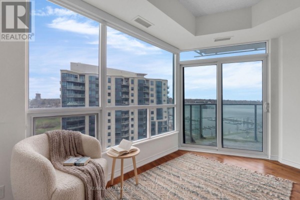 Corner window seat with armchair and side table overlooking the bay and marina. - 1303 - 37 Ellen Street, Barrie
