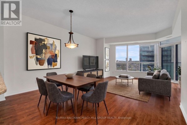 Dining area with a wooden table and four chairs, adjacent to a living area. - 1303 - 37 Ellen Street, Barrie